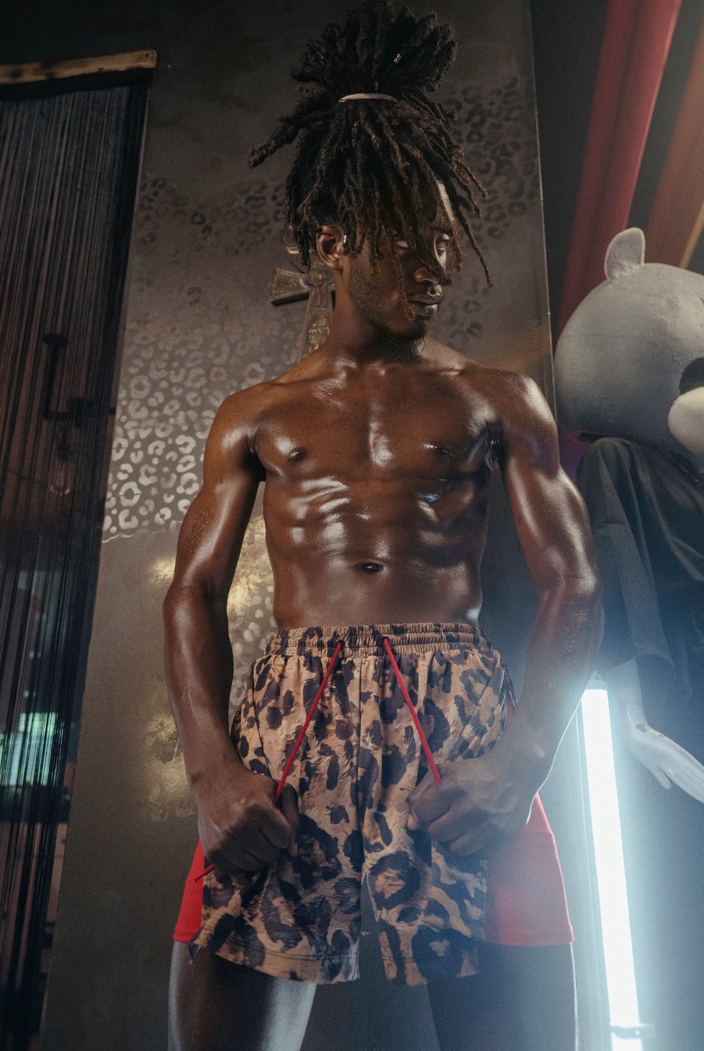 Man wearing The Shaka Shorts, which feature red shorts with leopard print draping.