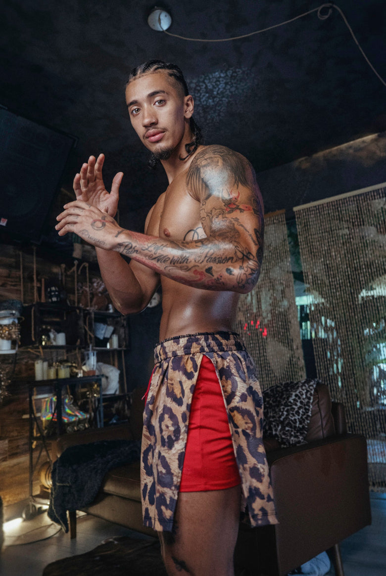 Man wearing The Shaka Shorts, which feature red shorts with leopard print draping.