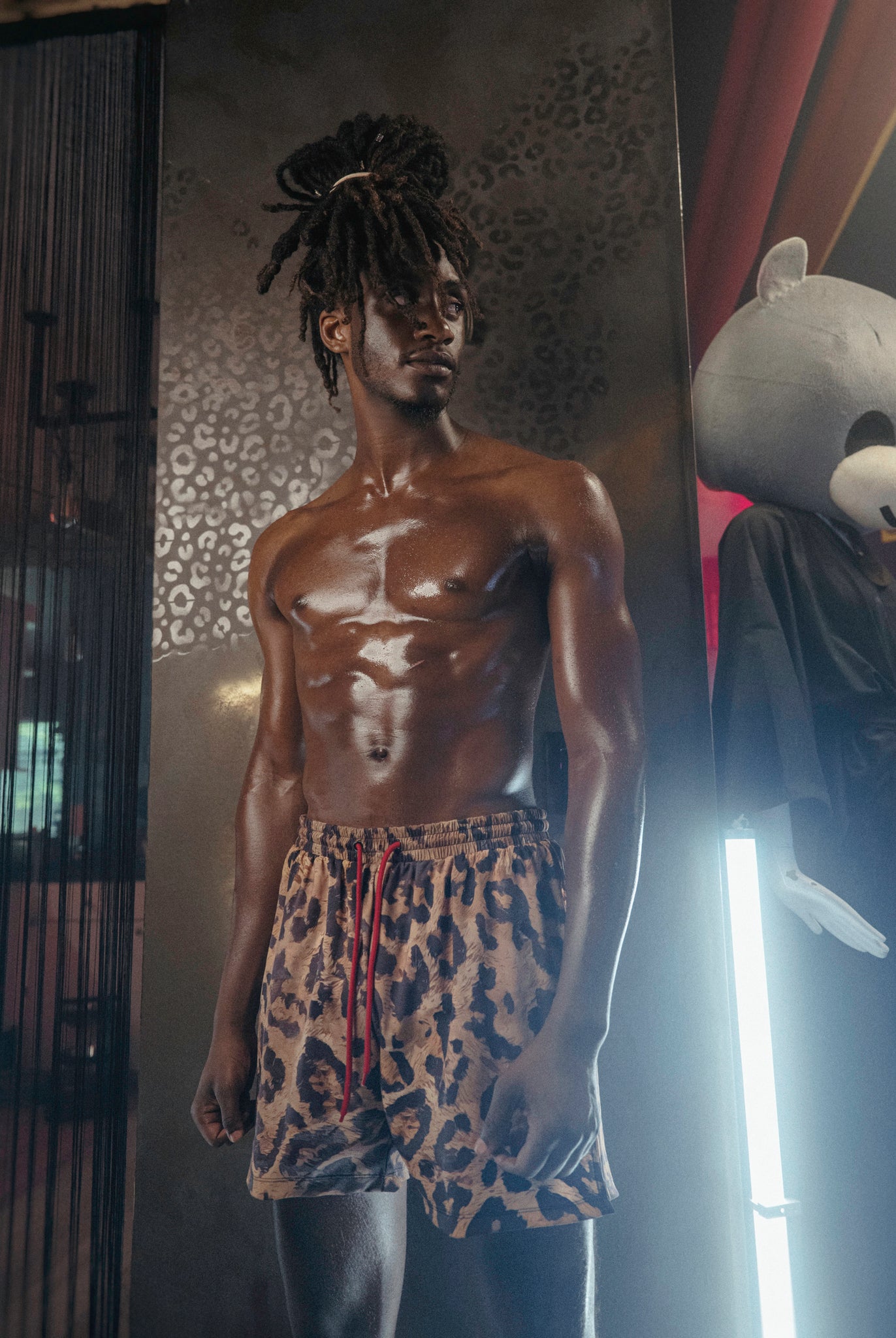 Man wearing The Shaka Shorts, which feature red shorts with leopard print draping.