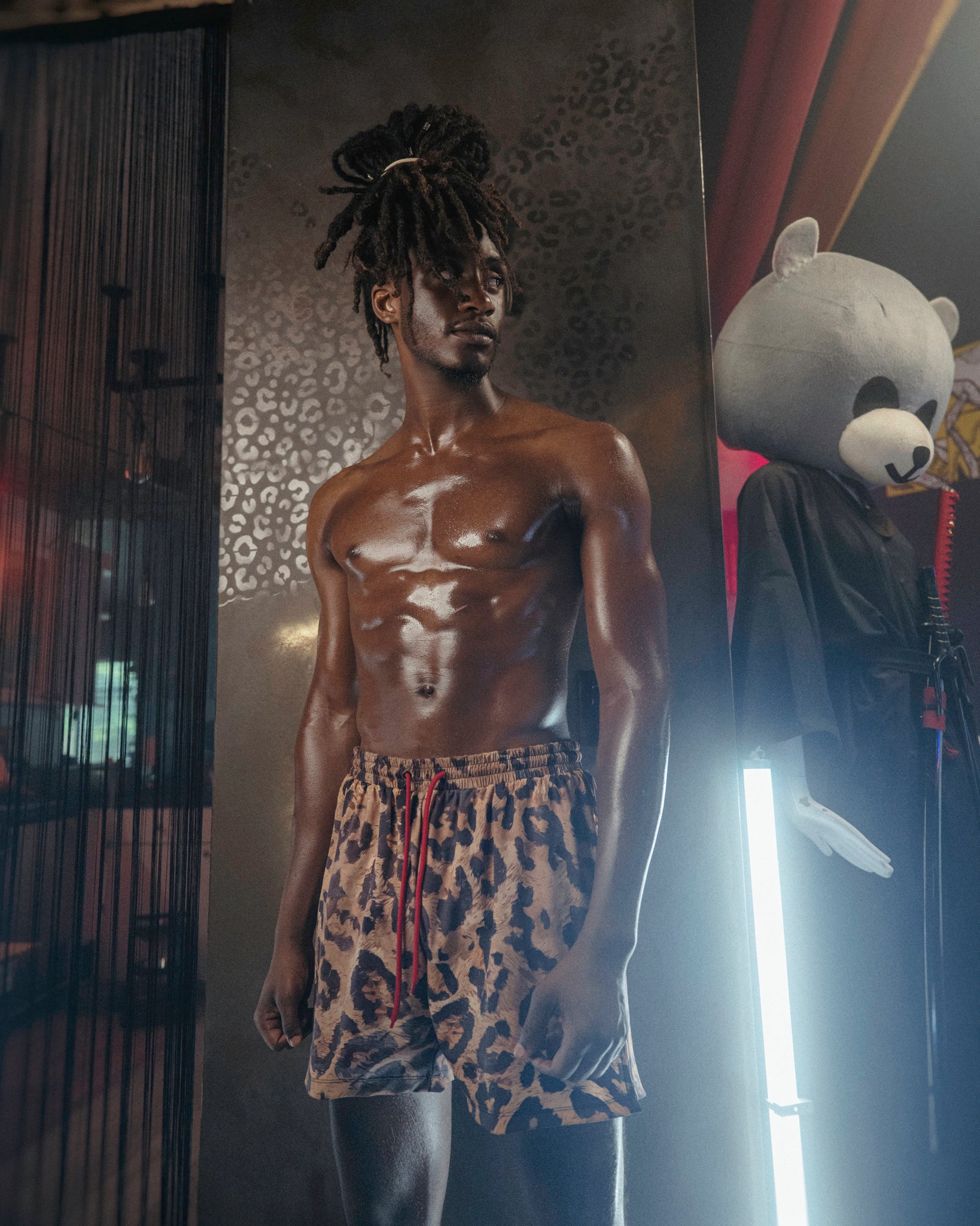 Man wearing The Shaka Shorts, which feature red shorts with leopard print draping.