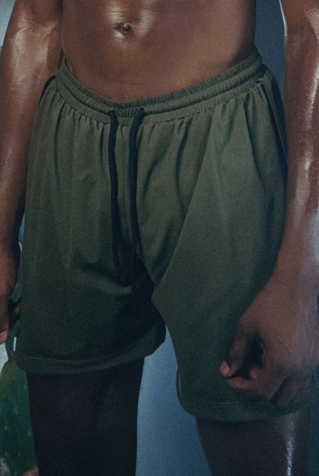 A person wearing the Jobari Shorts from Ruin Rally, which feature military green and black outer shorts with a graphic pattern on the inner shorts.