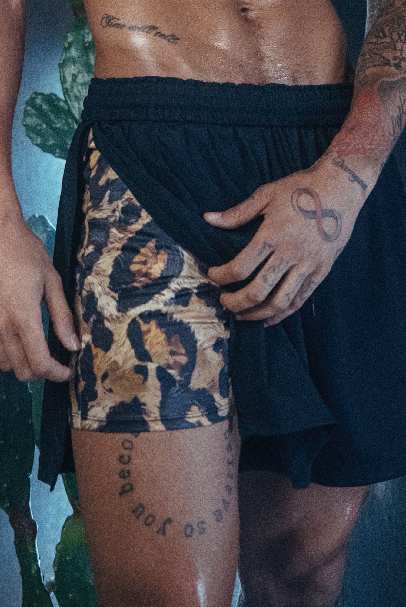 Man in Duku shorts, which feature a Cheetah print inside short and black outer draping short.