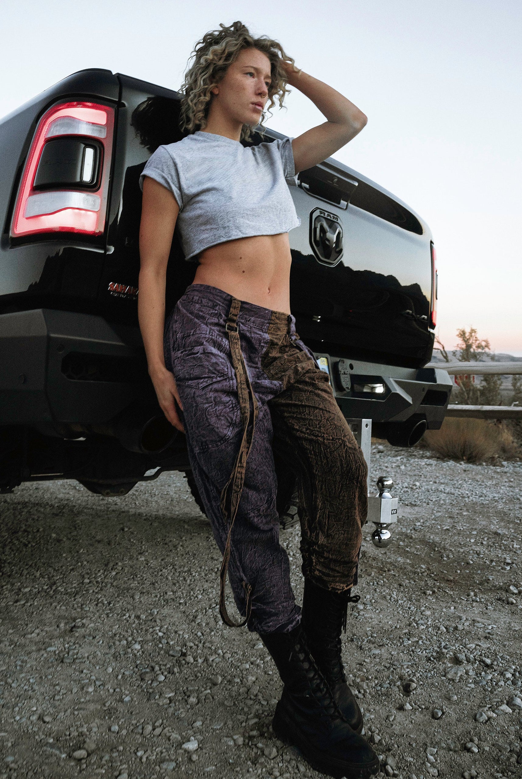 Person wearing the Berghain pants standing in a desert with a black vehicle in the background.