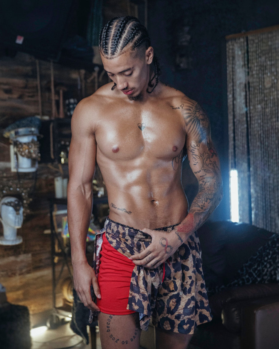 Man wearing The Shaka Shorts, which feature red shorts with leopard print draping.