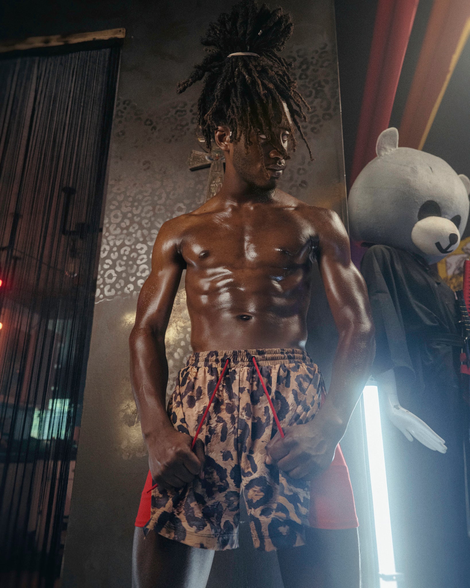 Man wearing The Shaka Shorts, which feature red shorts with leopard print draping.