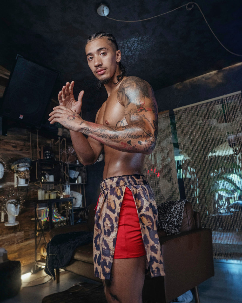 Man wearing The Shaka Shorts, which feature red shorts with leopard print draping.