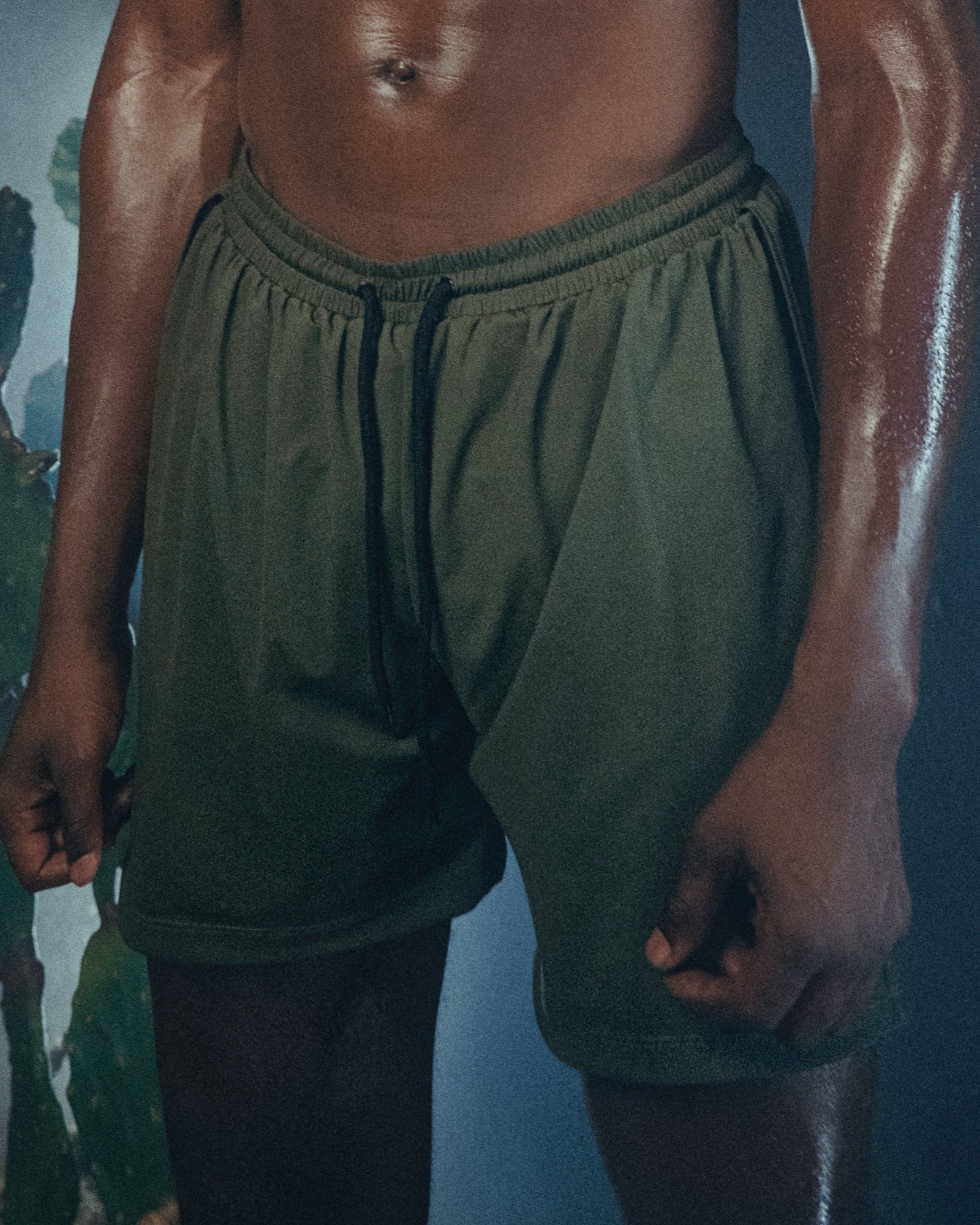 A person wearing the Jobari Shorts from Ruin Rally, which feature military green and black outer shorts with a graphic pattern on the inner shorts.