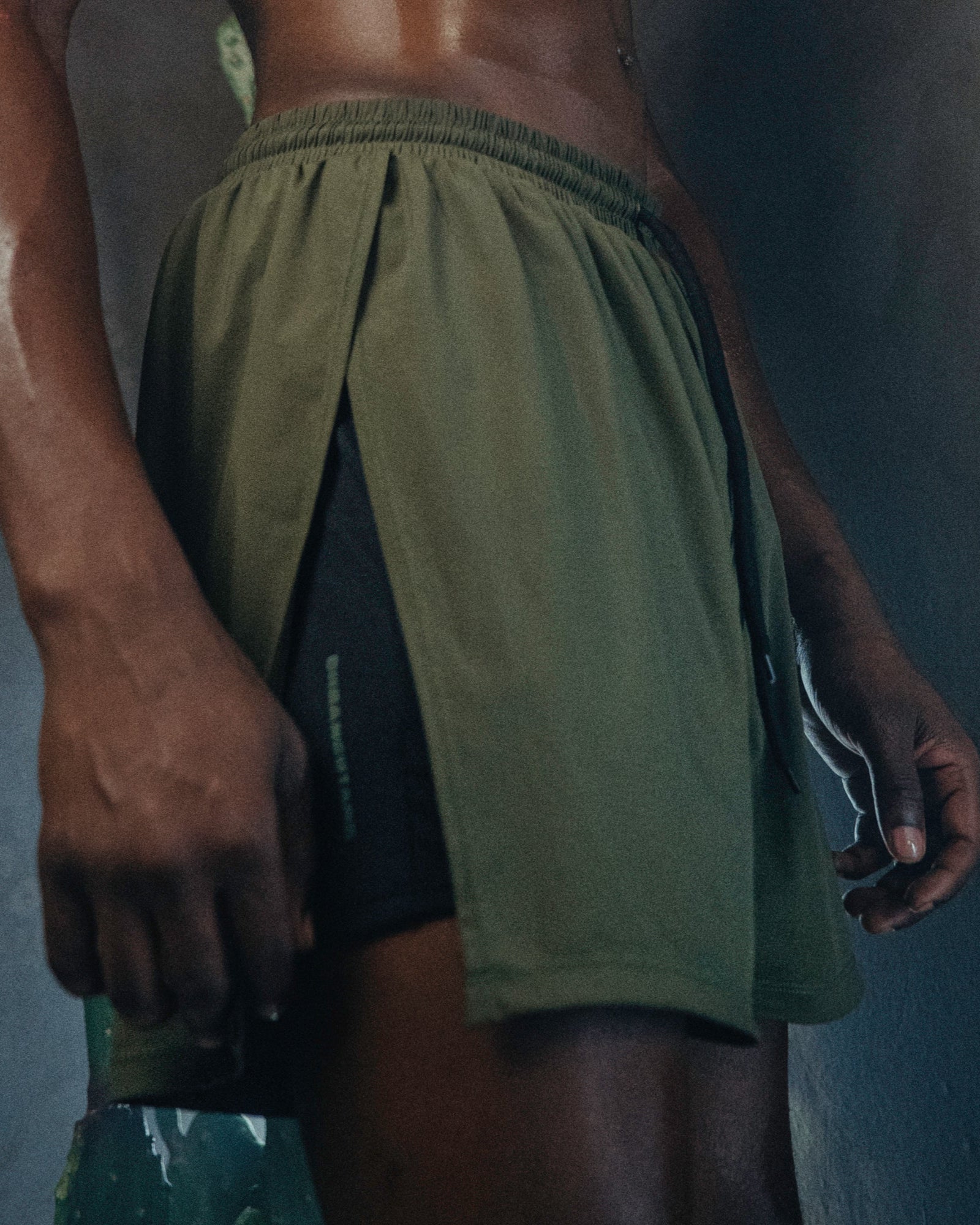 A person wearing the Jobari Shorts from Ruin Rally, which feature military green and black outer shorts with a graphic pattern on the inner shorts.