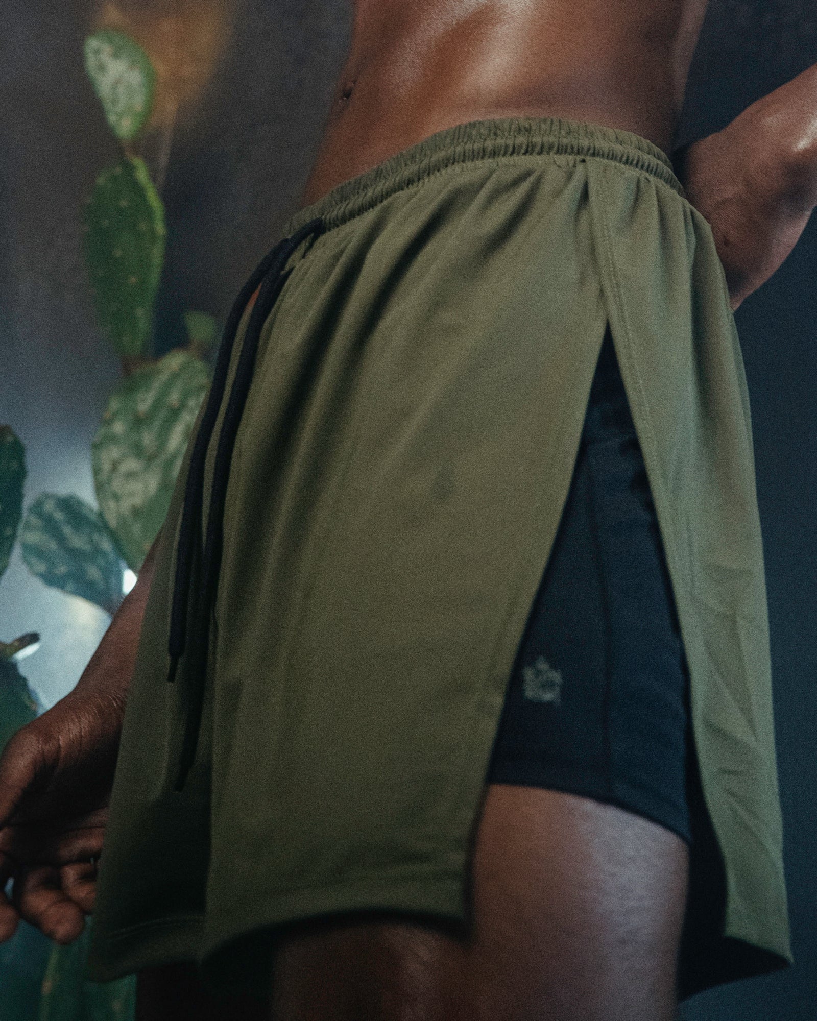 A person wearing the Jobari Shorts from Ruin Rally, which feature military green and black outer shorts with a graphic pattern on the inner shorts.
