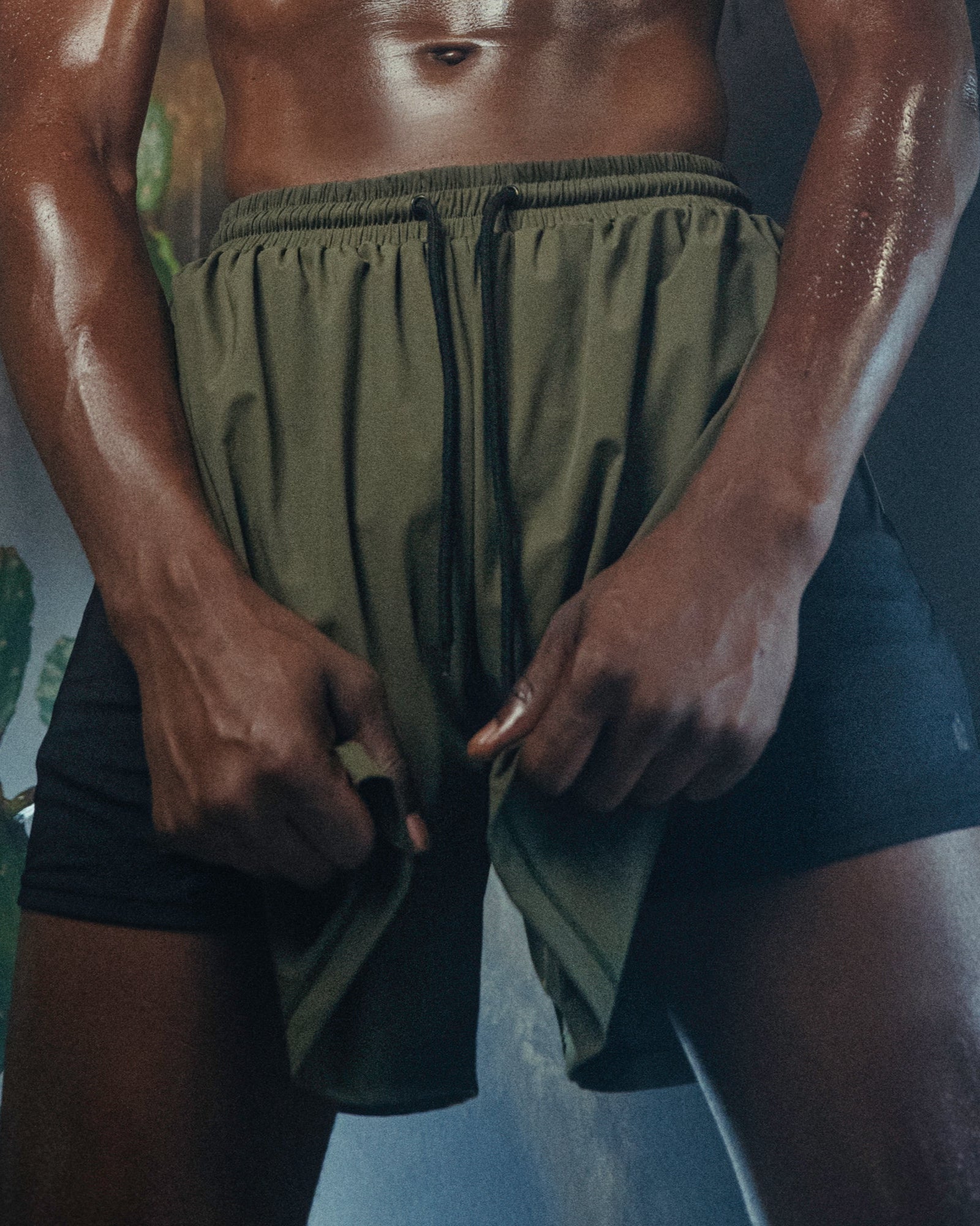 A person wearing the Jobari Shorts from Ruin Rally, which feature military green and black outer shorts with a graphic pattern on the inner shorts.