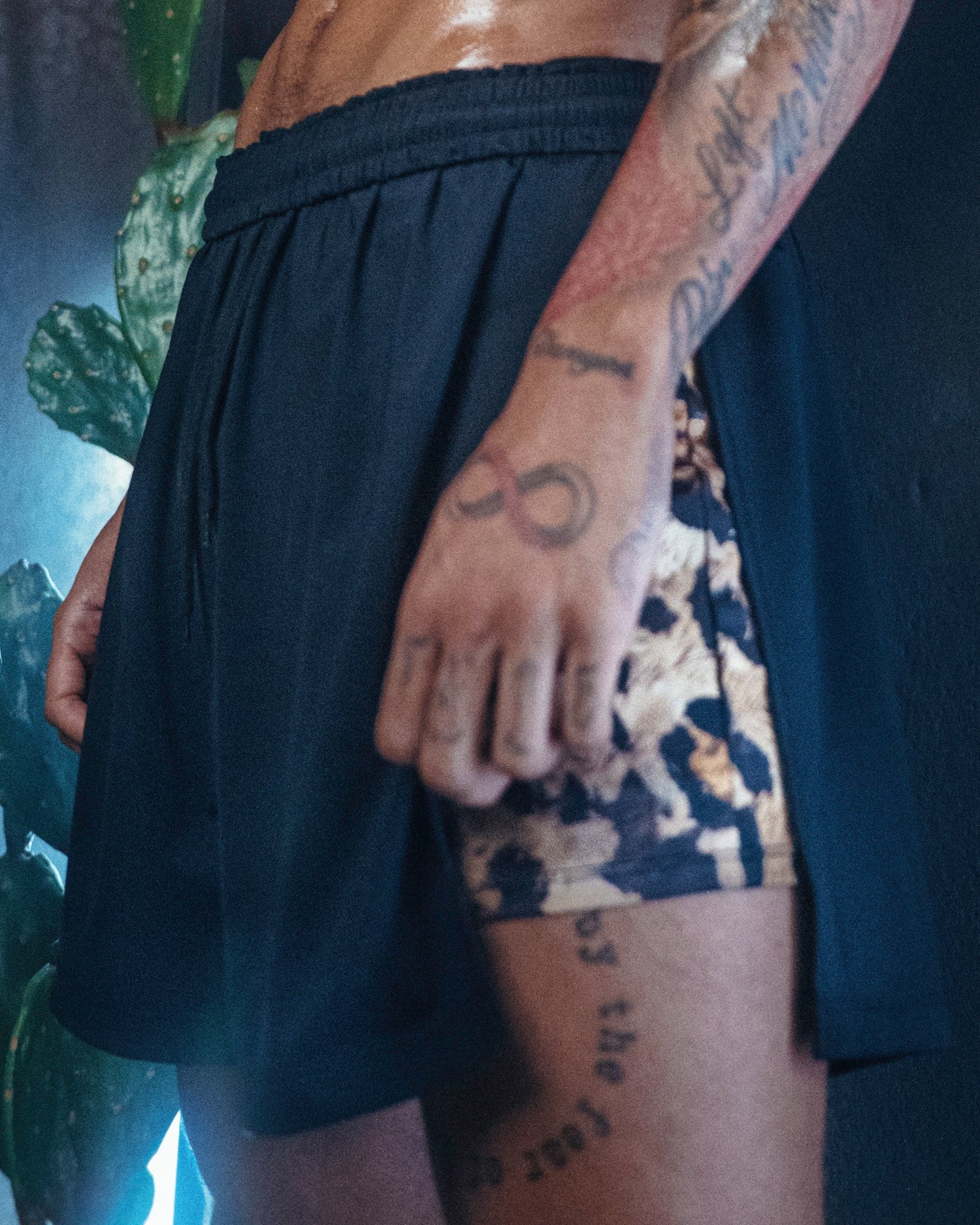 Man in Duku shorts, which feature a Cheetah print inside short and black outer draping short. 