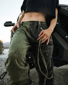 Person wearing the Berghain pants standing in a desert with a black vehicle in the background.