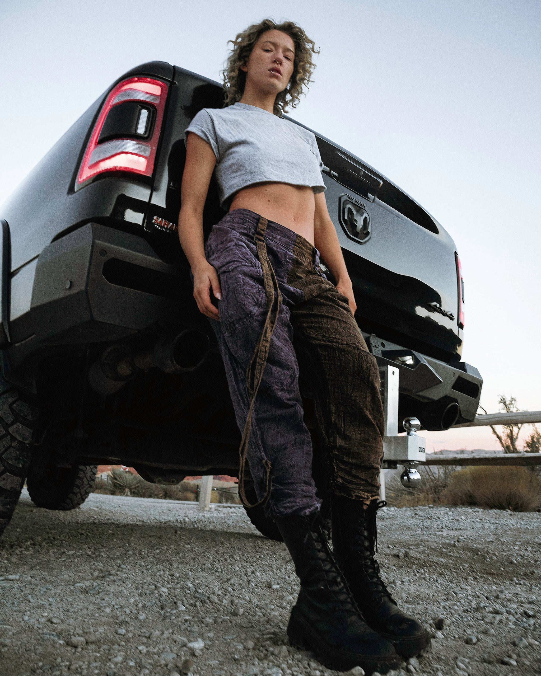 Person wearing the Berghain pants standing in a desert with a black vehicle in the background.